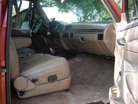 1995 Ford Bronco - The interior of a truck is shown, tan seats and dashboard with visible air vents.