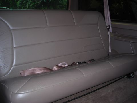 1995 Ford Bronco - The rear bench seat of a 1995 Ford Bronco features tan leather upholstery and visible seatbelts.