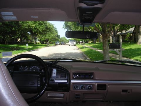 1995 Ford Bronco - View from inside a vehicle, looking out at a residential street with trees and houses.