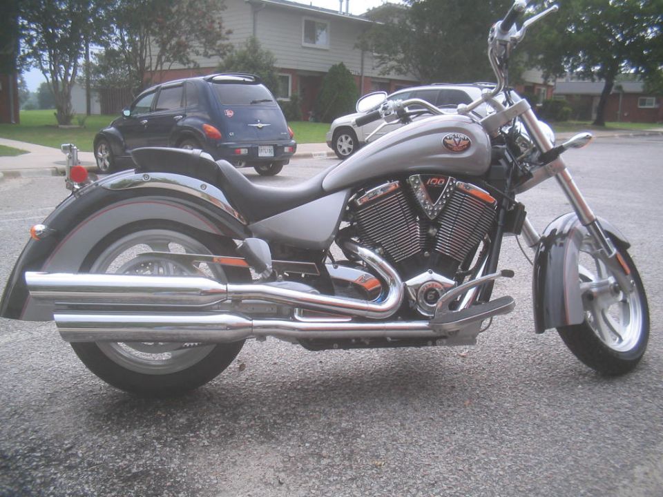 Silver Victory cruiser motorcycle, right side view, parked in residential lot