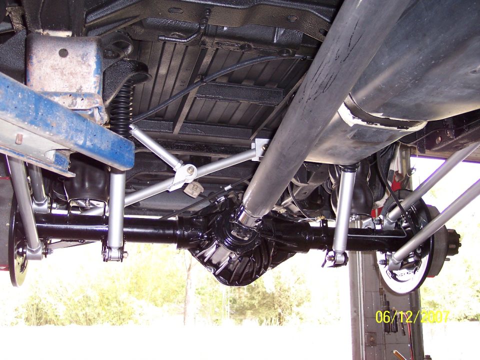 Undercarriage view showing rear axle, driveshaft, suspension links and exhaust on a lift
