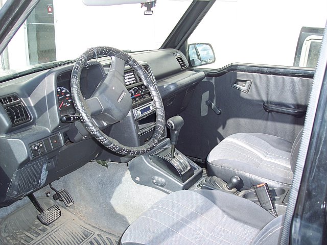 Interior view of a Suzuki Sidekick showing the dashboard, steering wheel, center console with automatic shifter, and seats