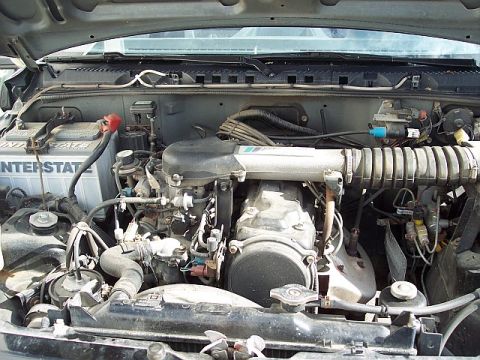 1995 Ford Bronco - The engine bay of a vehicle is shown, the battery and air intake system.