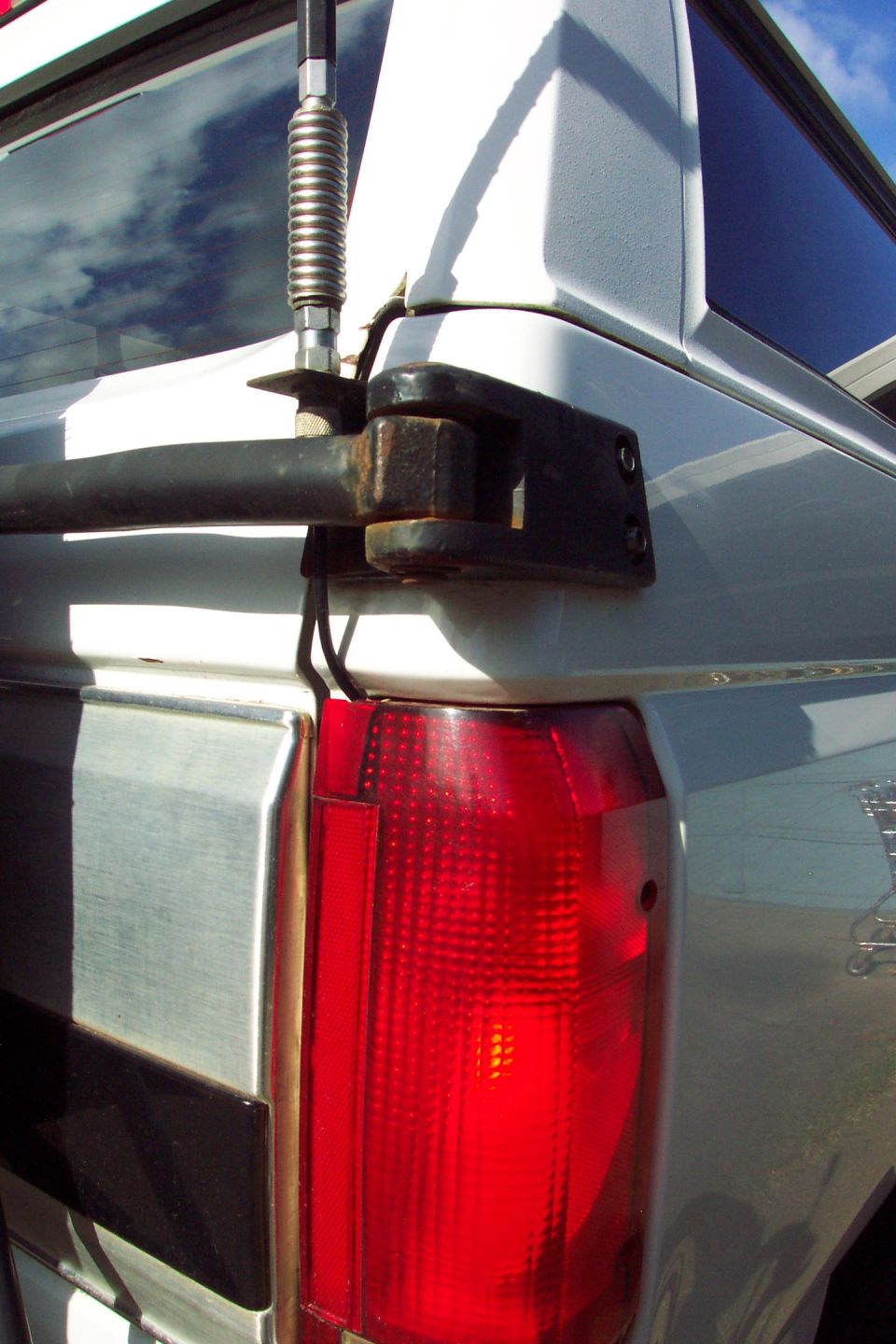 CB Radio Antenna Mount 
Mounted to Tire Carrier Bracket 
(can't depend on the swing arm pin for good ground)
Swing arm in latched position.

Coax routed through tail light.  Used a round file to make a small little notch in top of tail light lens.