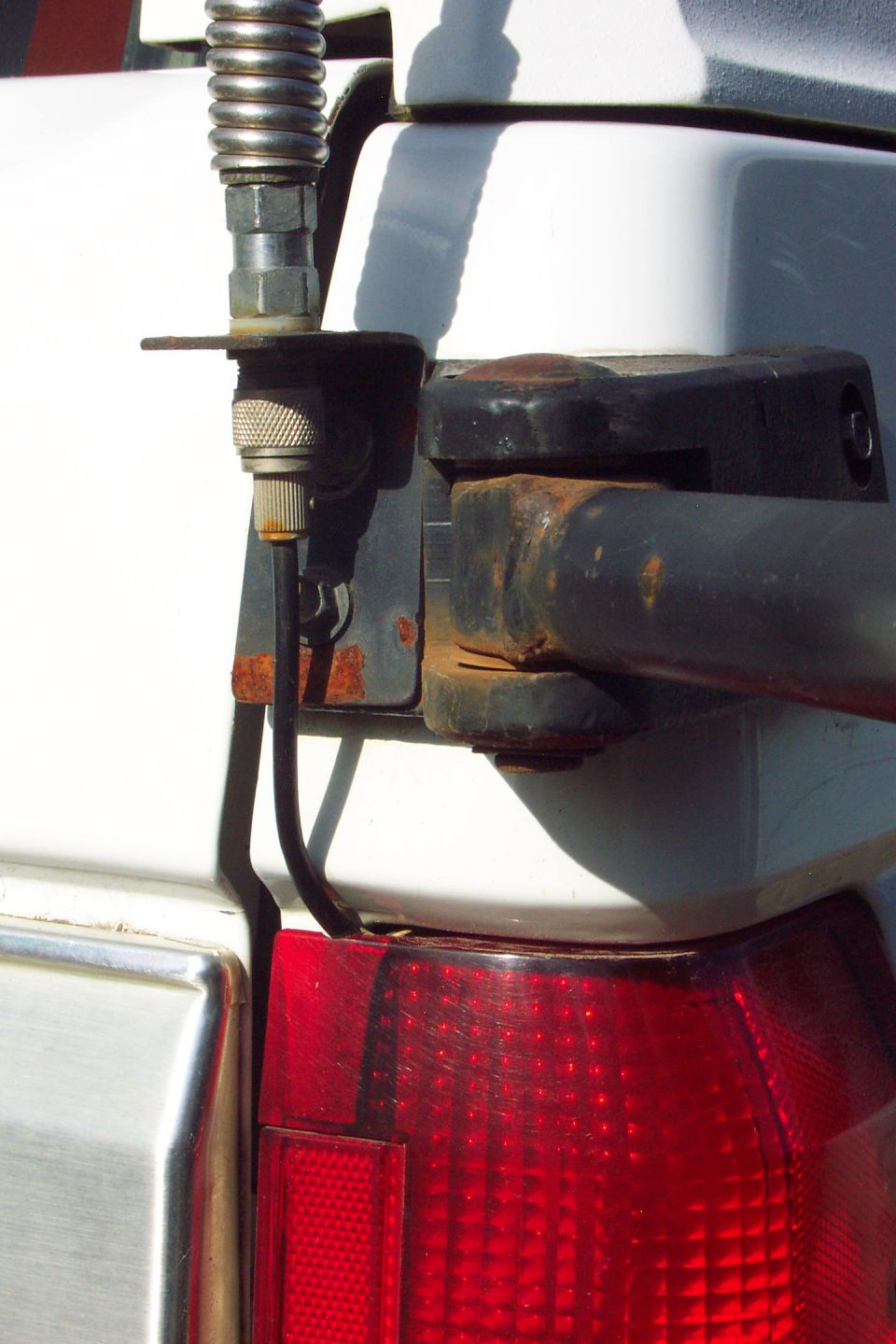 Close-up of trailer hitch wiring connector and pintle mount above a vehicle tail light