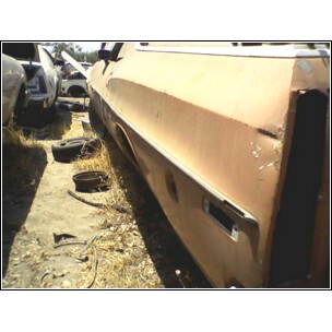 1973 Ford Ranchero - Rusted car body panel in a junkyard setting with other vehicle parts visible.