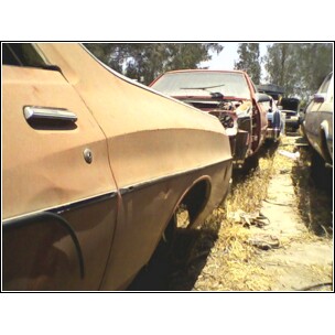 1973 Ford Ranchero - Multiple vehicles are parked in an outdoor lot, appearing to be abandoned or awaiting repair.