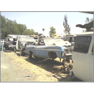 1973 Ford Ranchero - A light blue 1968 Ford Ranchero convertible sits in a junkyard, stripped of its wheels and other parts.