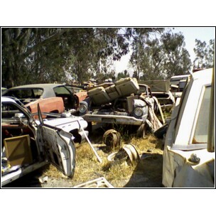 1973 Ford Ranchero - A collection of discarded vehicle parts and bodies are seen in a junkyard, with the SuperMotors.net logo at the bottom.