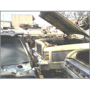 1973 Ford Ranchero - A collection of vehicles in a salvage yard, showing various states of disrepair.