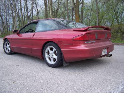 1995 Ford Probe - A red Ford Probe is shown from the rear three-quarter view, parked outdoors with trees in the background.