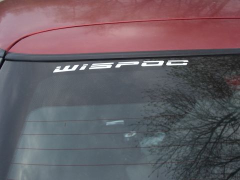 1995 Ford Probe - A white decal reading 'WISPOC' is visible on the rear window of a red vehicle, with a Supermotors logo at the bottom right.