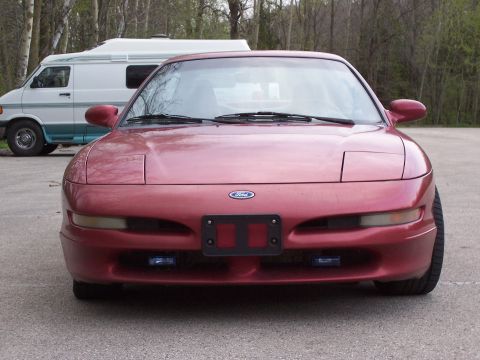 1995 Ford Probe - Front view of a red 1995 Ford Probe parked outdoors with a van in the background.