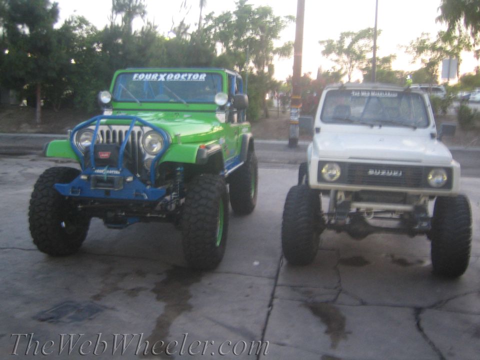 White Suzuki Samurai and green Jeep parked side-by-side, both lifted with large tires