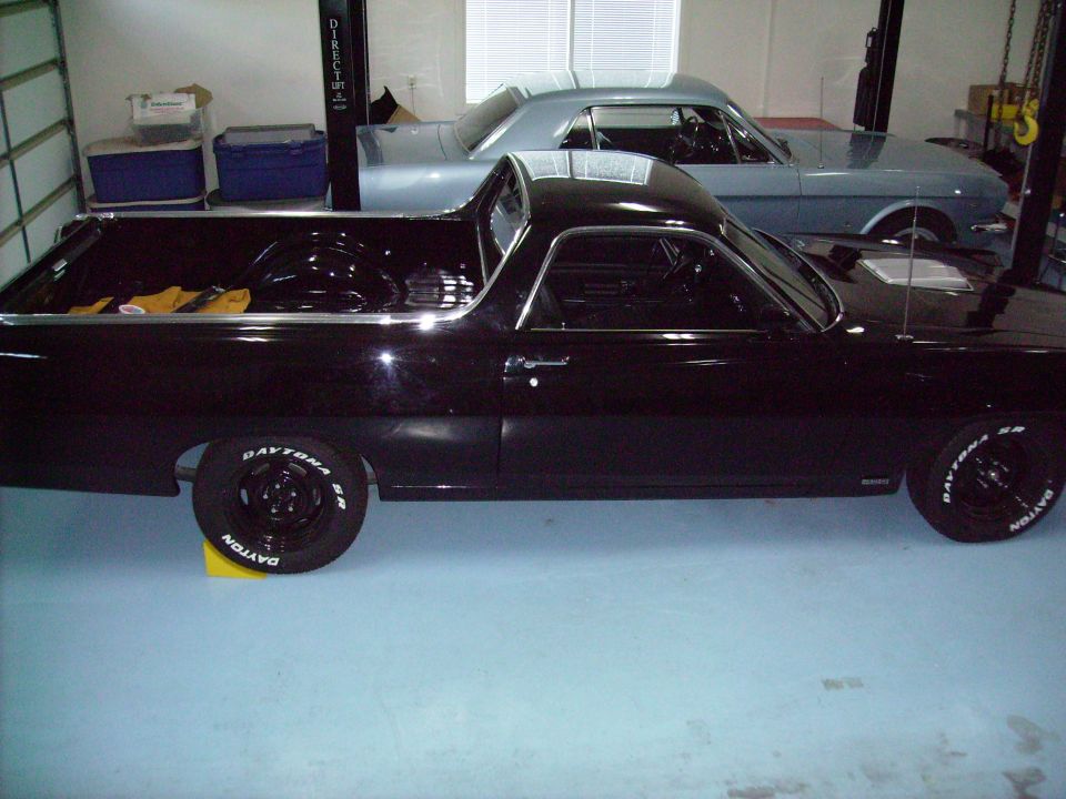 Black 1970 Ford Ranchero parked in garage next to a silver coupe