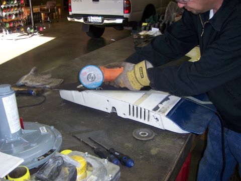 1991 Ford Bronco - A person uses an angle grinder on a white and blue automotive part.
