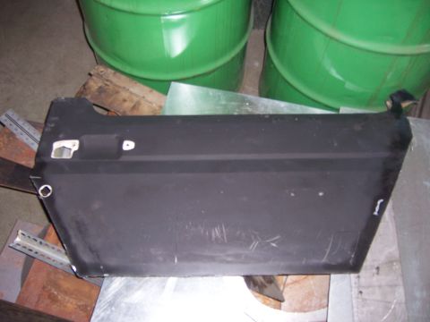 1991 Ford Bronco - Black car door panel with cutouts for handle and mirror, resting on metal supports.