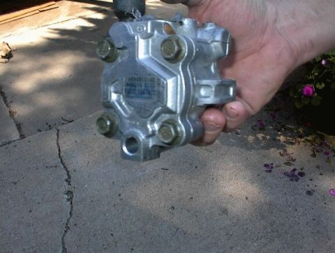 1997 Ford Taurus - A power steering pump is held in a hand, with part numbers visible on its casing.
