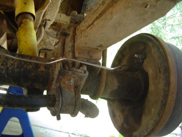 Rusty rear axle assembly with yellow shock absorber and brake drum