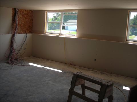 1984 Ford Bronco - An unfinished room with exposed wiring and a window overlooking a driveway and garage.