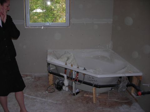 1984 Ford Bronco - A bathtub is installed in a room under construction, with plumbing visible.