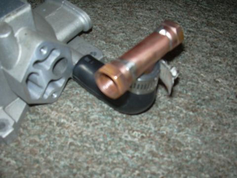 1996 Ford Crown Victoria - Close-up of an automotive part with a copper pipe attached, resting on a carpeted surface.