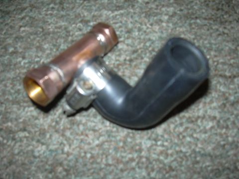 1996 Ford Crown Victoria - A copper plenum fitting with a brass end is shown next to a black rubber hose with a metal clamp, resting on a carpeted surface.