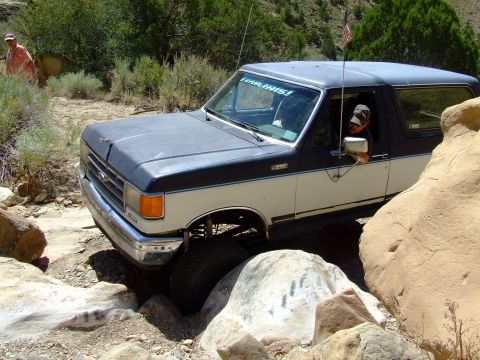 1987 Ford Bronco - Ford Bronco tackles a challenging off-road course with large rocks.