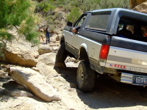 1987 Ford Bronco - 1987 Ford Bronco tackles a challenging rocky trail with its tires angled.