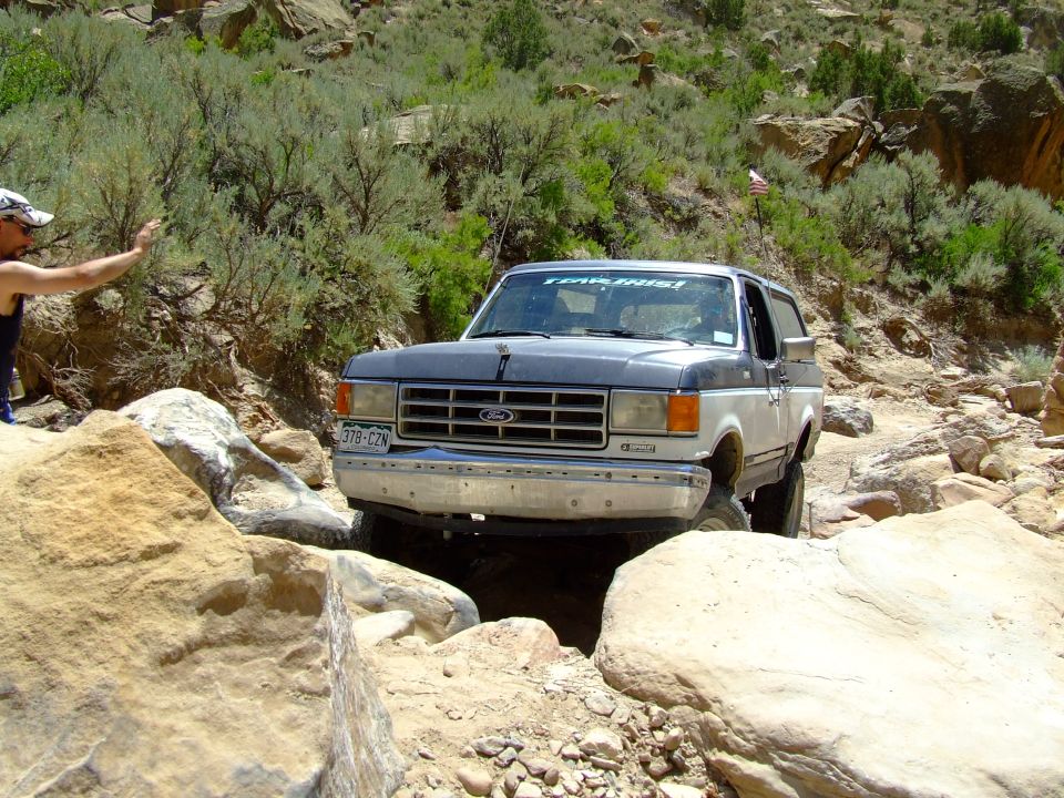 Two-tone gray and white Ford Bronco navigating rocky terrain