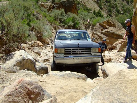 1987 Ford Bronco - Ford Bronco tackles a challenging off-road path in a canyon.