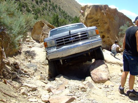 1987 Ford Bronco - A Ford truck is shown off-roading on a rocky, mountainous terrain.