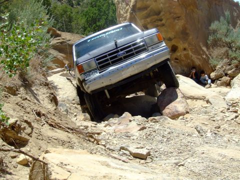 1987 Ford Bronco - A 1987 Ford Bronco maneuvers over large rocks on a challenging off-road path.