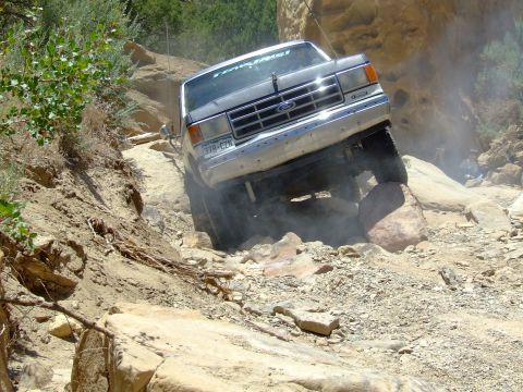 1987 Ford Bronco - This 1987 Ford Bronco tackles a challenging rocky terrain, kicking up dust as it maneuvers.
