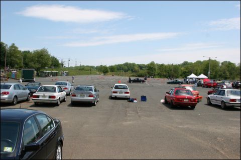 2001 Mercury Grand Marquis - Multiple cars are parked in an outdoor lot, some with cones nearby, under a partly cloudy sky.