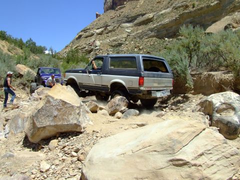 1987 Ford Bronco - A 1987 Ford Bronco tackles a challenging rocky trail, with a Jeep following closely behind on the off-road adventure.