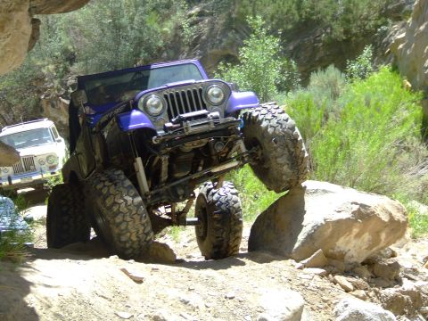 1987 Ford Bronco - Jeep Wrangler navigating a rocky off-road course, with another vehicle in the background.