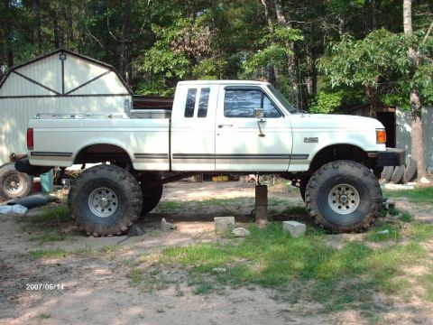 1990 Ford F-150 - A white 1990 Ford F-150 pickup truck is shown with a lifted suspension and oversized tires.