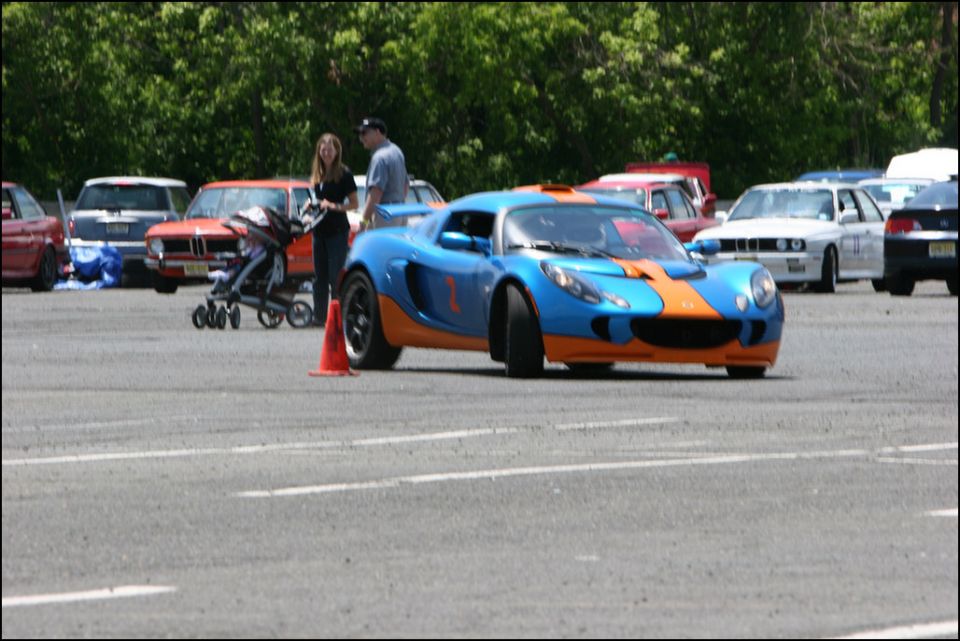 Blue and orange race car with racing decals, seen from a 3/4 front angle on a paved surface
