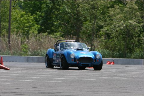 2001 Mercury Grand Marquis - A blue AC Cobra replica navigates a race track, marked with racing decals and the number 09.