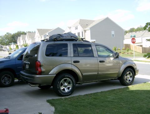 2004 Dodge Durango - A gold 2004 Dodge Durango is parked in a driveway next to a blue truck, with houses in the background.
