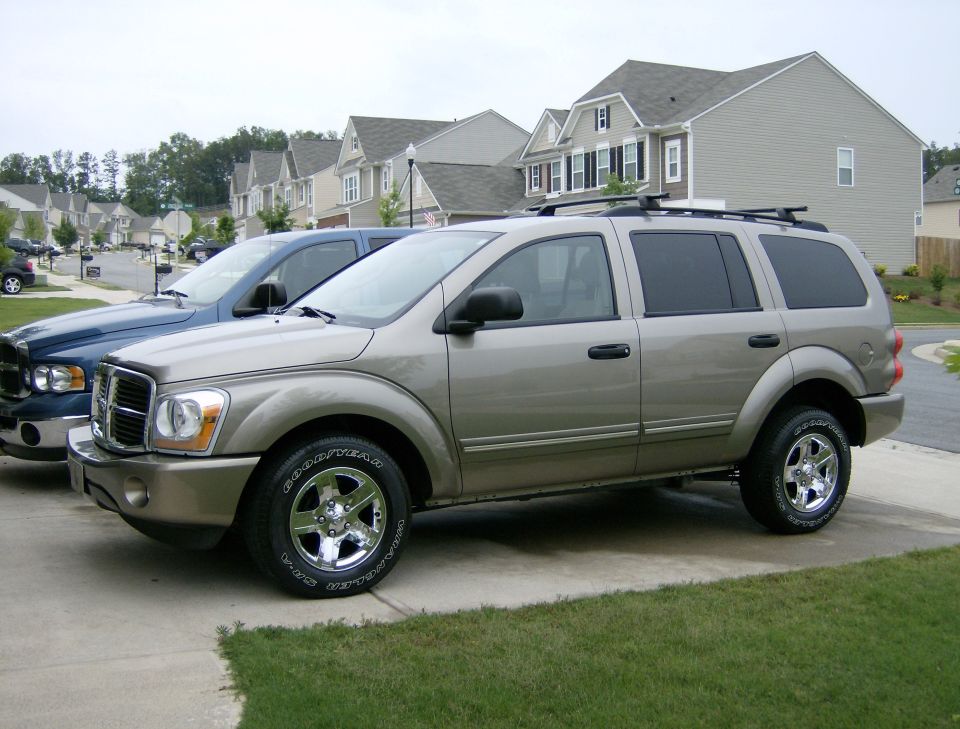 Gold Dodge Durango SUV with chrome wheels parked in a suburban driveway