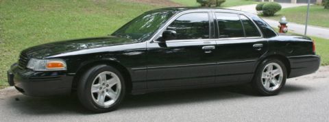 2002 Ford Crown Victoria - Side view of a black 2002 Ford Crown Victoria sedan parked on a residential street.