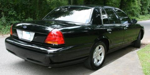 2002 Ford Crown Victoria - A black 2002 Ford Crown Victoria is shown from the rear, parked on the side of a road.