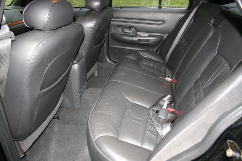 Back seats and door panel of a car. Black leather seats with seatbelts