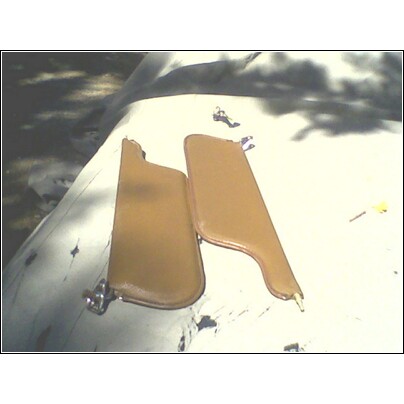 1973 Ford Ranchero - Two tan sun visors are laid out on a white surface, possibly for sale or repair.
