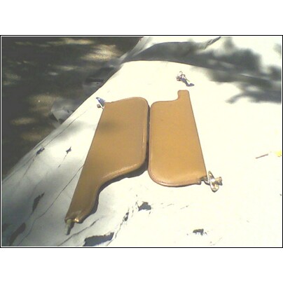 1973 Ford Ranchero - Two tan sun visors are laid out on a white surface, possibly a car roof, with shadows from trees overhead.