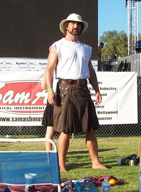 1990 Ford Bronco - Man in kilt and hat stands outdoors in front of a banner with text.