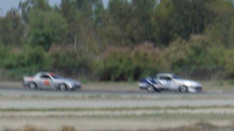 1990 Ford Probe - Two sports cars race on a track, one is a silver 1990 Ford Probe.