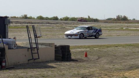 1990 Ford Probe - A white race car with blue stripes and the number 86 is driving on a track, with another car visible in the distance.